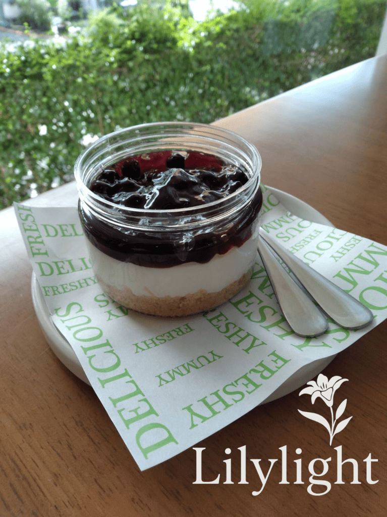 Blueberry cheesecake jar dessert served on a wooden table with natural sunlight
