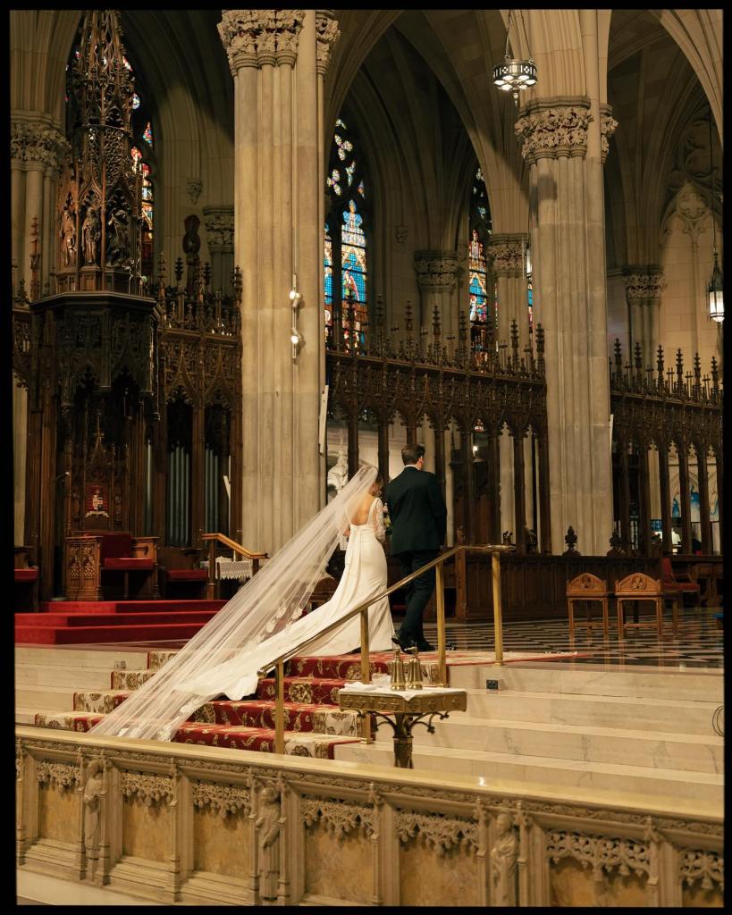 Bride and groom walking together inside St. Patrick’s Cathedral during a wedding ceremony in New York City