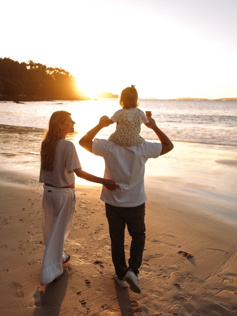 A family walking together by the sea at sunset, symbolizing love growing beyond marriage into family life